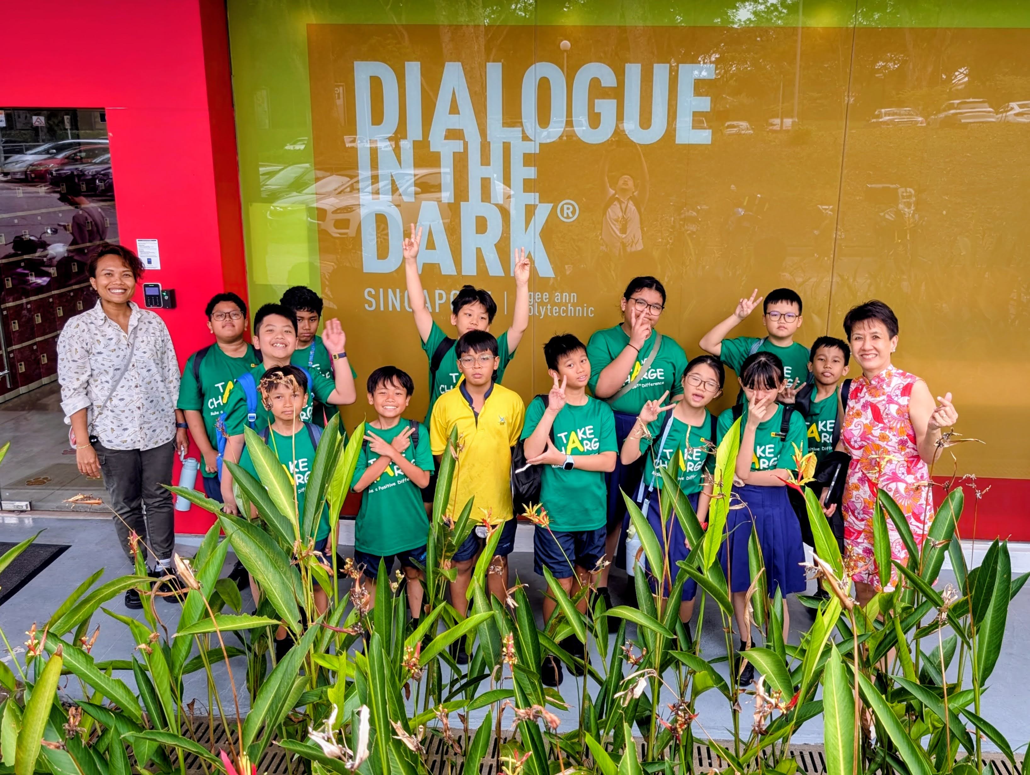 Our students posing for a group photo with their teacher and our principal in front of Dialogue In The Dark at Ngee Ann Polytechnic